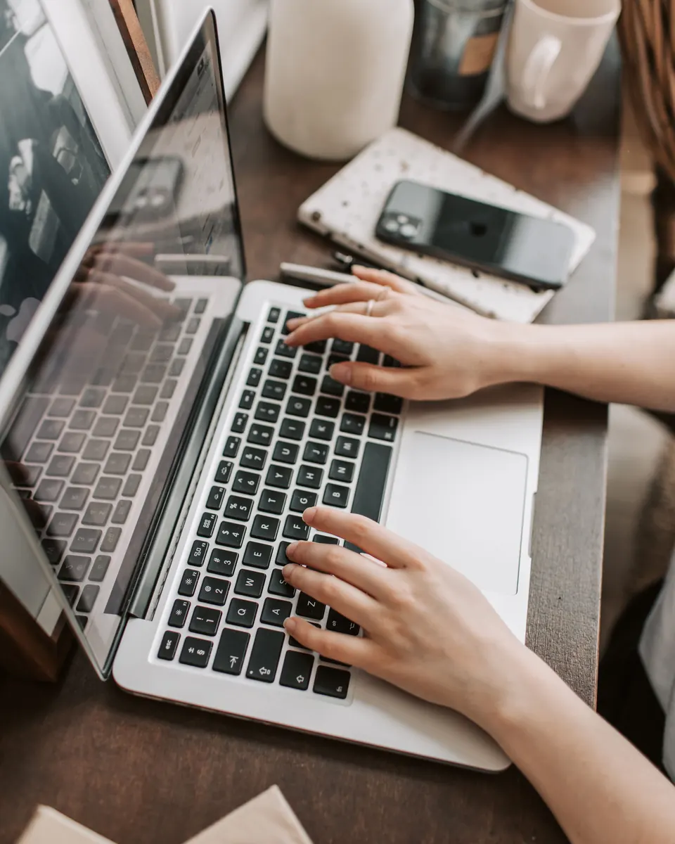 Freelancer typing on a laptop at a warm home workspace