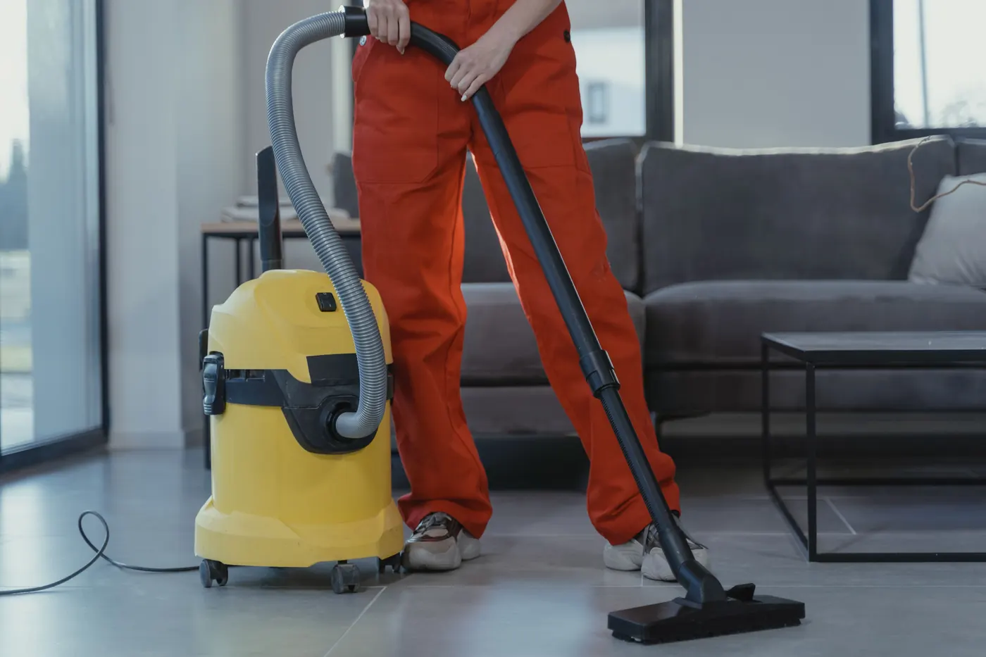 Professional cleaner vacuuming a modern living room